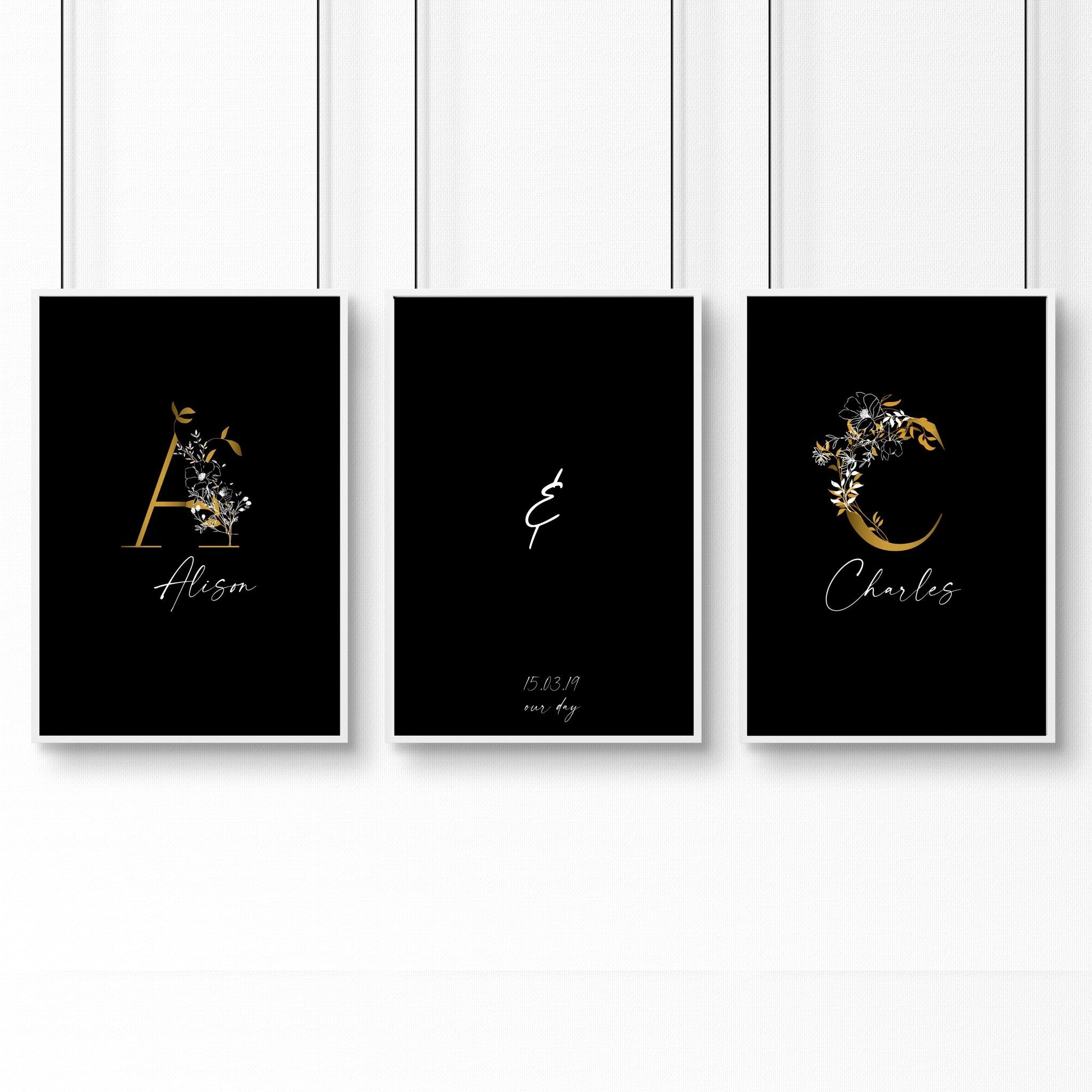 Set of 3 personalized wall art prints featuring botanical monogram designs in white, black, and gold on a black background.