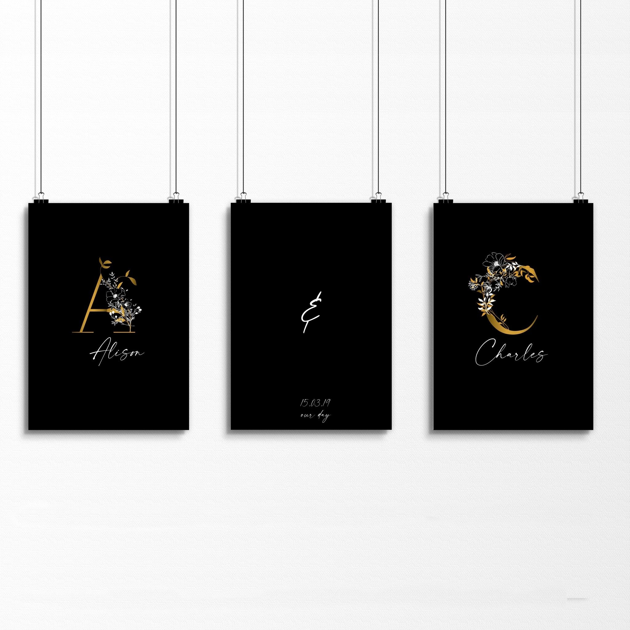 Set of 3 personalized wall art prints featuring botanical monogram designs in white, black, and gold on a black background.