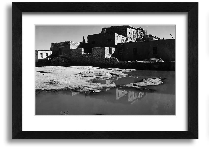 Framed print of Ansel Adams' Acoma Pueblo 3, showcasing intricate adobe structures and dramatic sky.