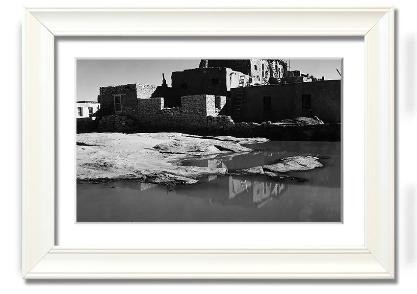 Framed print of Ansel Adams' Acoma Pueblo 3, showcasing intricate adobe structures and dramatic sky.