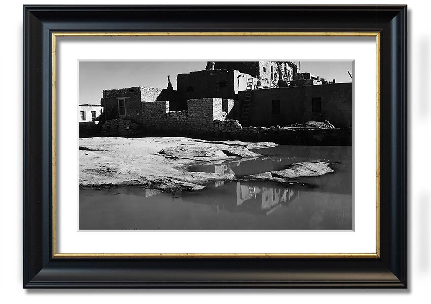 Framed print of Ansel Adams' Acoma Pueblo 3, showcasing intricate adobe structures and dramatic sky.