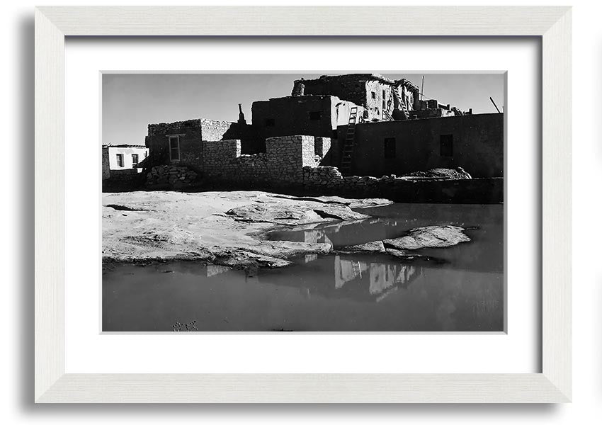 Framed print of Ansel Adams' Acoma Pueblo 3, showcasing intricate adobe structures and dramatic sky.