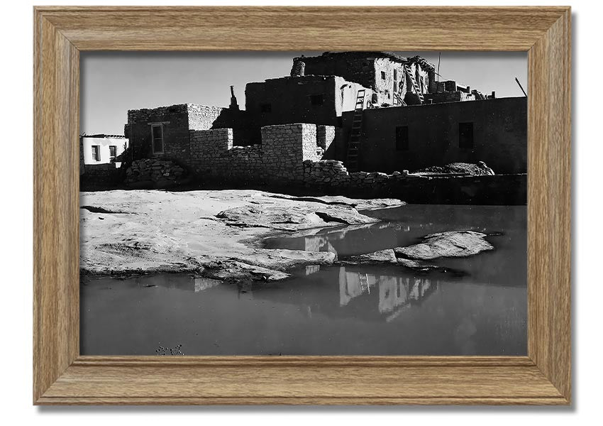 Framed print of Ansel Adams' Acoma Pueblo 3, showcasing intricate adobe structures and dramatic sky.