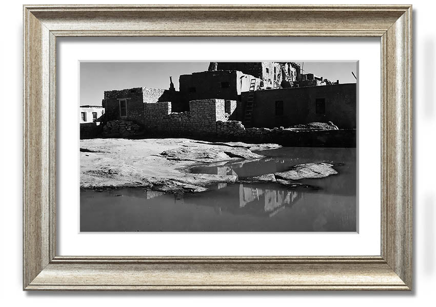 Framed print of Ansel Adams' Acoma Pueblo 3, showcasing intricate adobe structures and dramatic sky.