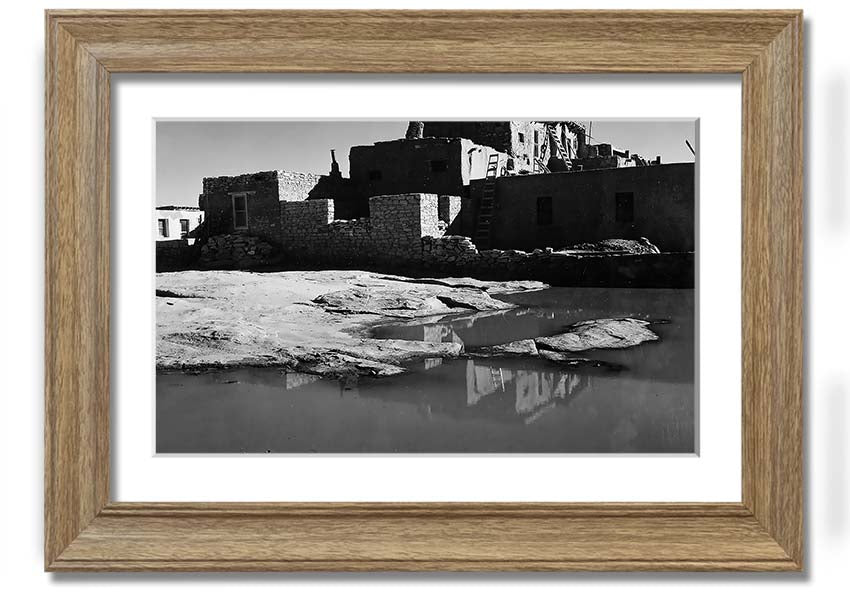 Framed print of Ansel Adams' Acoma Pueblo 3, showcasing intricate adobe structures and dramatic sky.