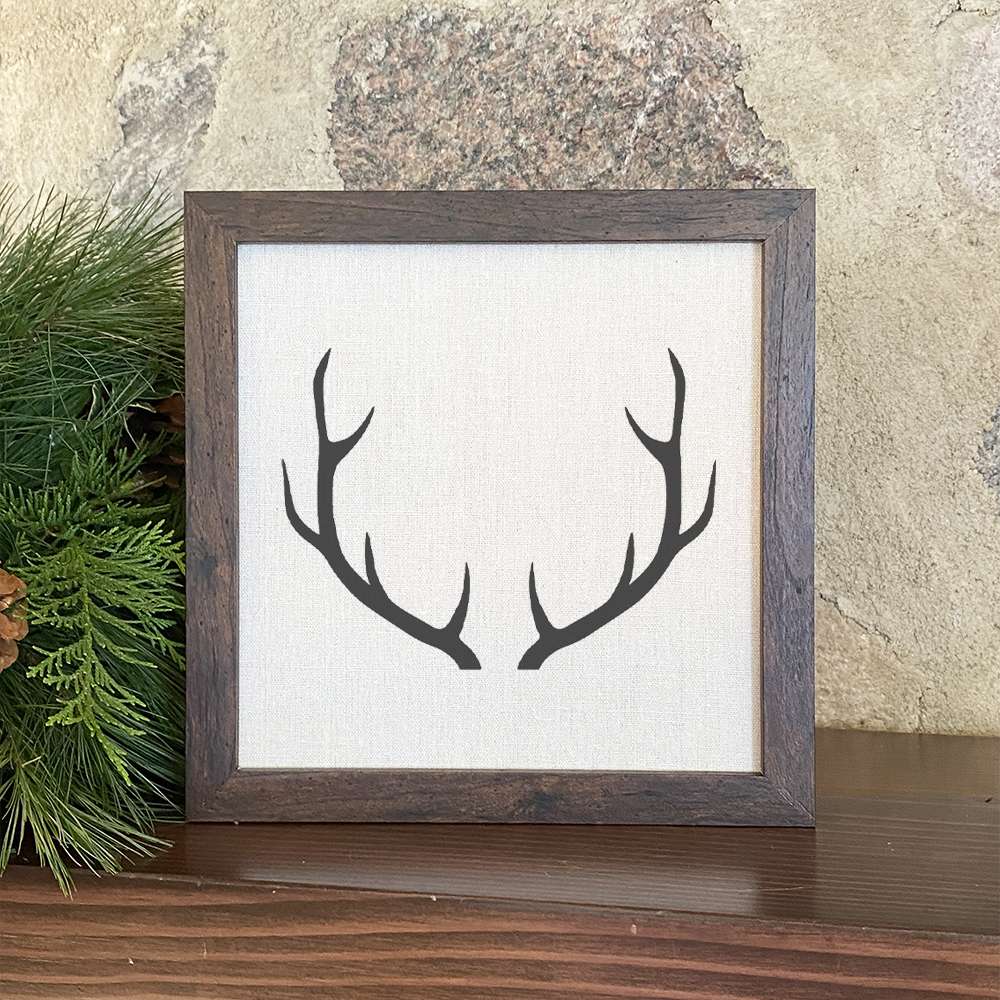 Antlers Framed Sign with a stylized wood frame, eco-friendly printing on a linen-look background.