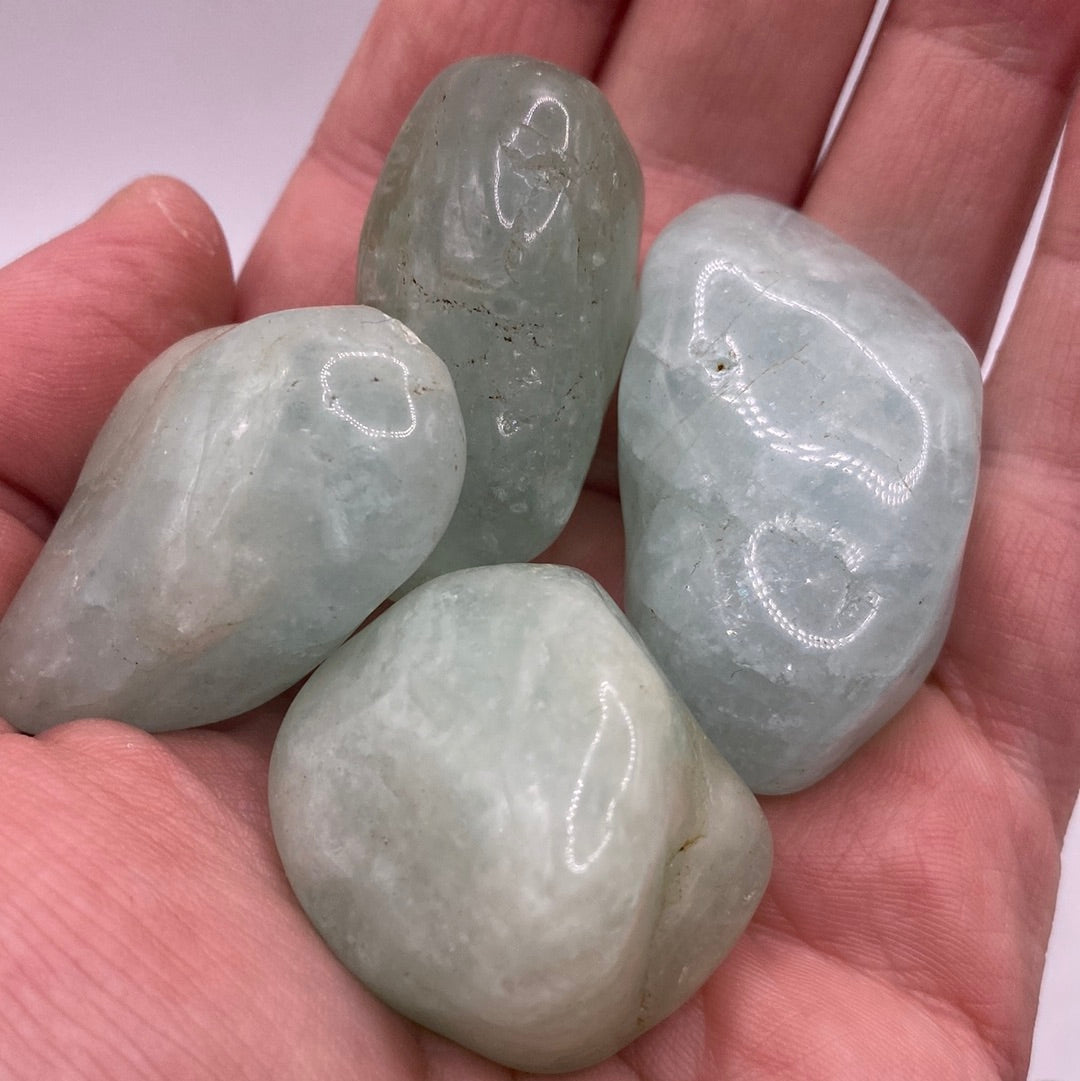 A collection of smooth, blue-green Aquamarine Tumbled stones, showcasing their natural beauty and calming energy.