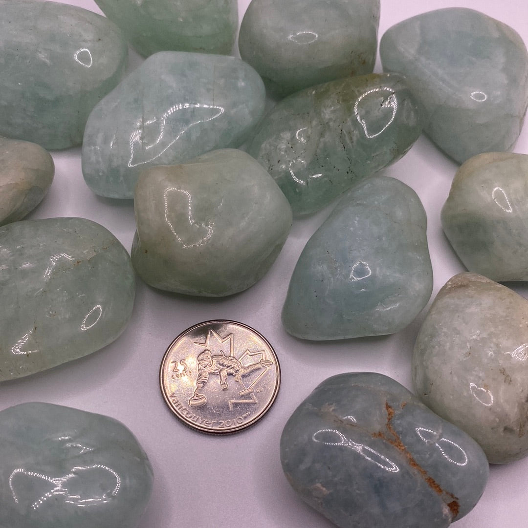 A collection of smooth, blue-green Aquamarine Tumbled stones, showcasing their natural beauty and calming energy.