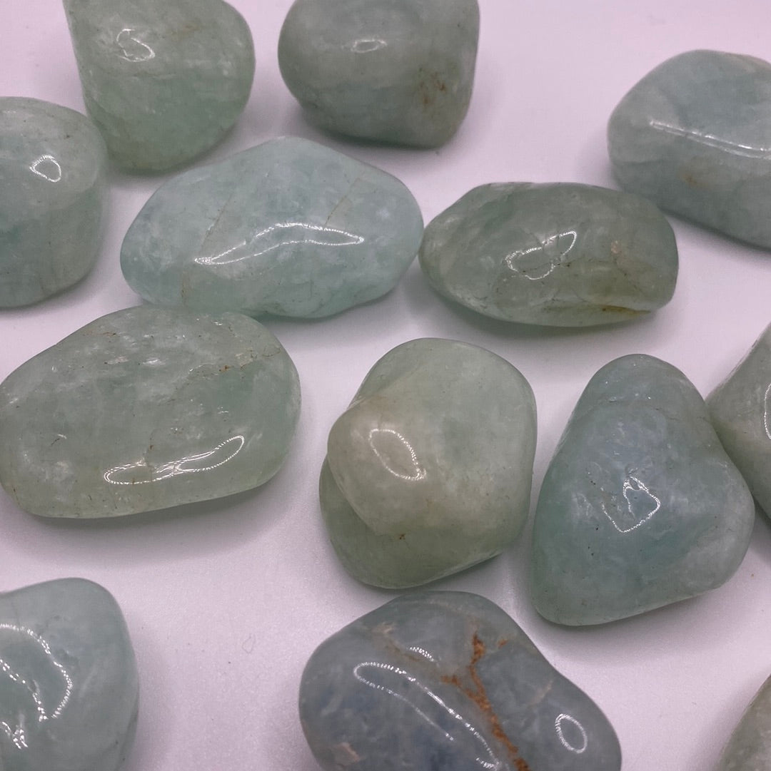 A collection of smooth, blue-green Aquamarine Tumbled stones, showcasing their natural beauty and calming energy.