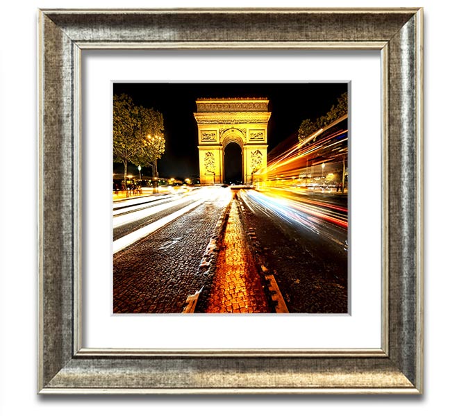 A beautifully framed print of the Arc De Triomphe illuminated at night, showcasing its architectural details and vibrant colors.