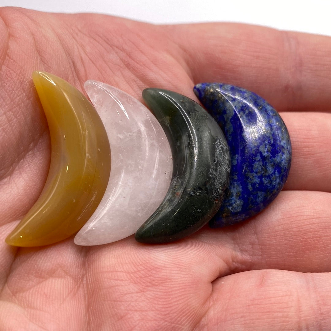 A collection of assorted mini moons made from various crystals including Lapis Lazuli, Amethyst, and Clear Quartz, each approximately 1 inch in size.