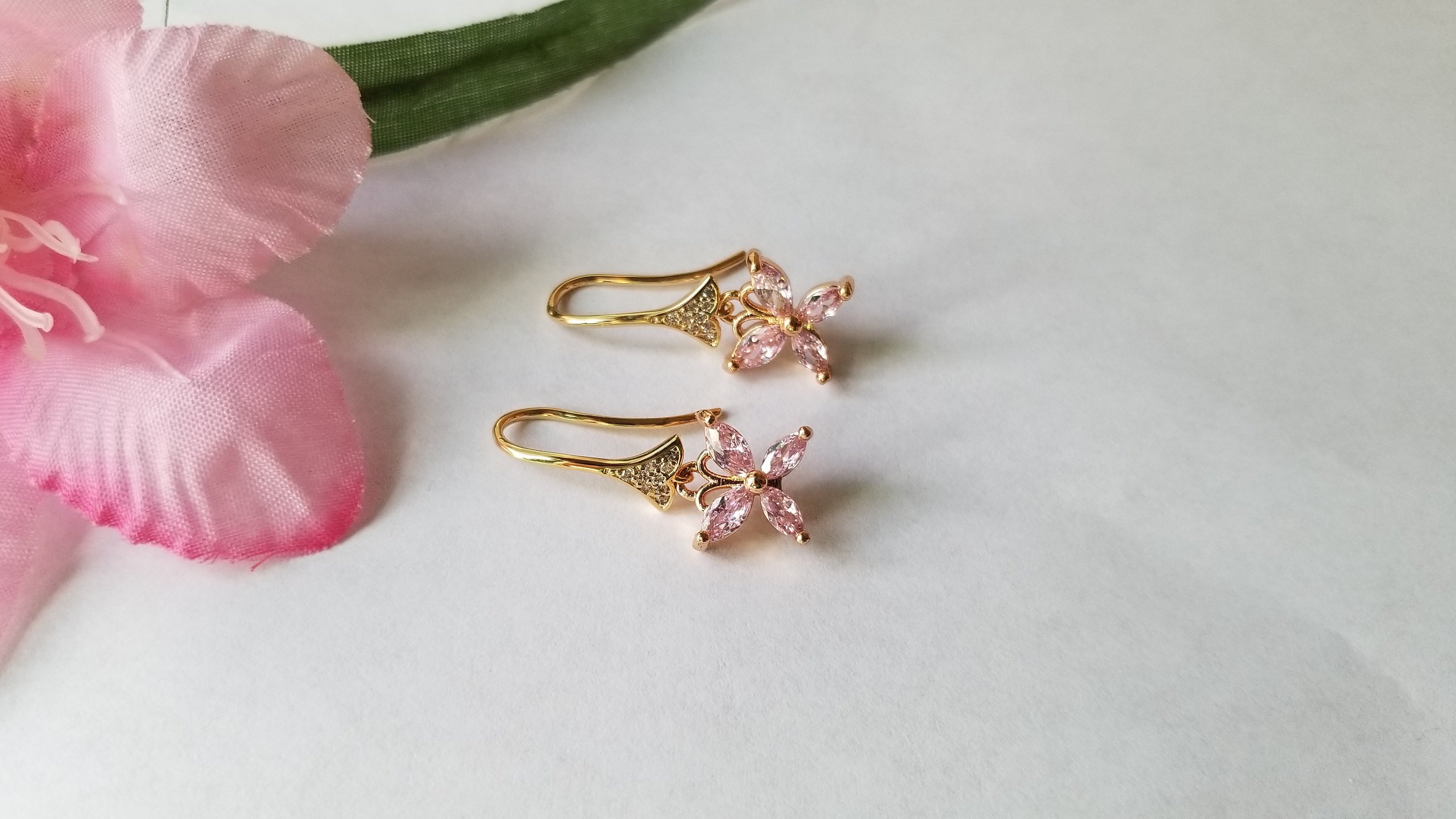 A pair of elegant baby pink butterfly earrings, beautifully crafted with 18K gold plating, showcasing intricate details and a charming design.