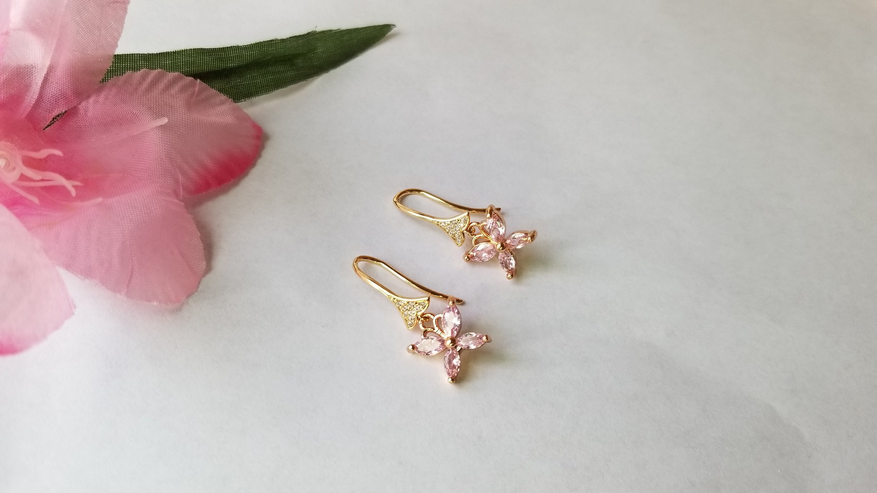 A pair of elegant baby pink butterfly earrings, beautifully crafted with 18K gold plating, showcasing intricate details and a charming design.