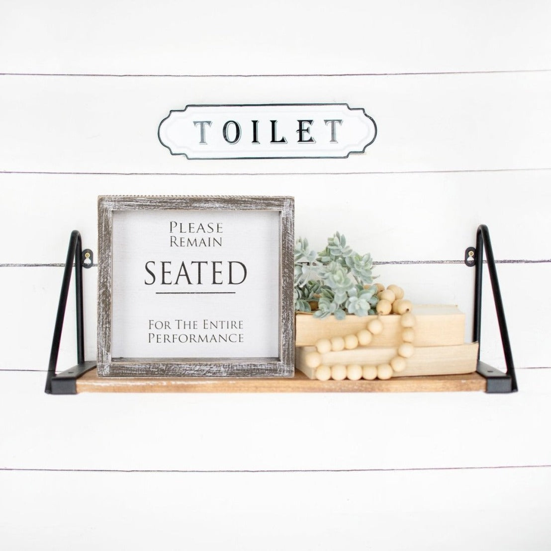 A versatile wood sign displaying 'Please Remain Seated For The Entire Performance' in black and white, suitable for bathrooms and theaters.