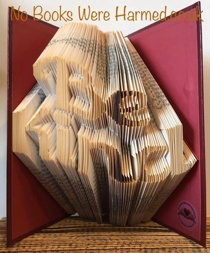 Handcrafted book art titled 'Be Kind', featuring intricately folded pages from vintage books, showcasing unique textures and colors.