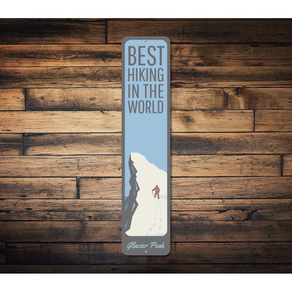 A decorative metal sign featuring the phrase 'Best Hiking in the World', showcasing a scenic mountain background, perfect for outdoor enthusiasts.