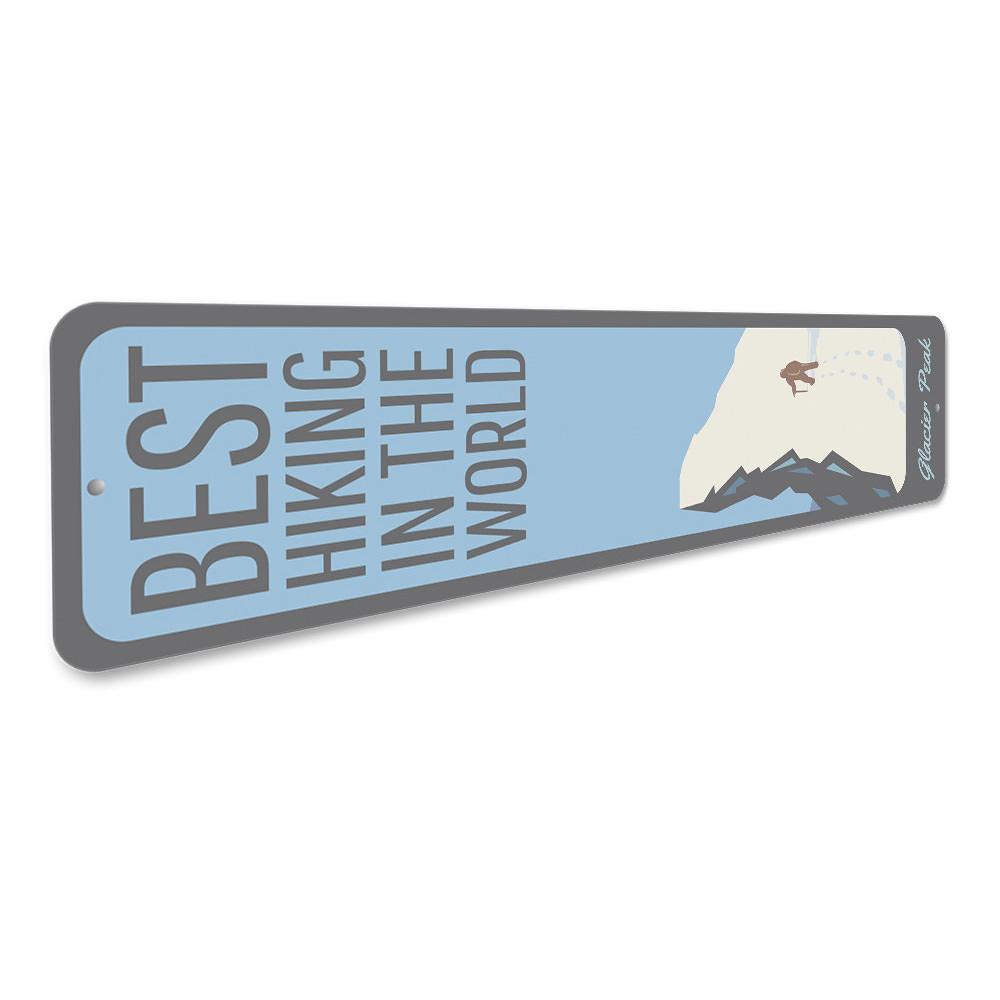 A decorative metal sign featuring the phrase 'Best Hiking in the World', showcasing a scenic mountain background, perfect for outdoor enthusiasts.