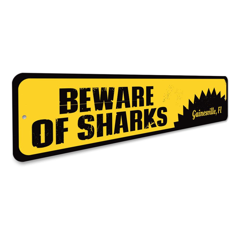 A decorative 'Beware of Sharks' sign made of aluminum, featuring vibrant colors and a playful design, perfect for beach houses and seafood restaurants.