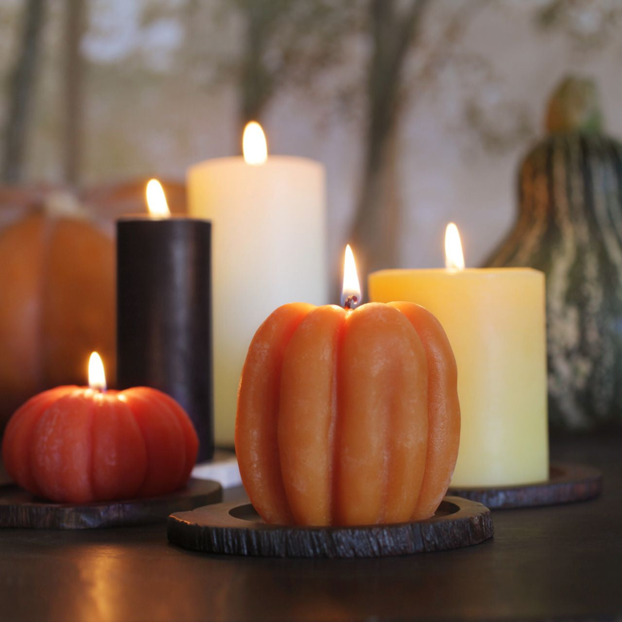 Three handcrafted beeswax pumpkin candles in dark orange, light orange, and natural colors, showcasing their unique designs and warm glow.