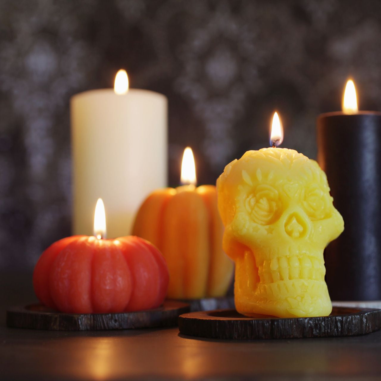 Three handcrafted beeswax pumpkin candles in dark orange, light orange, and natural colors, showcasing their unique designs and warm glow.