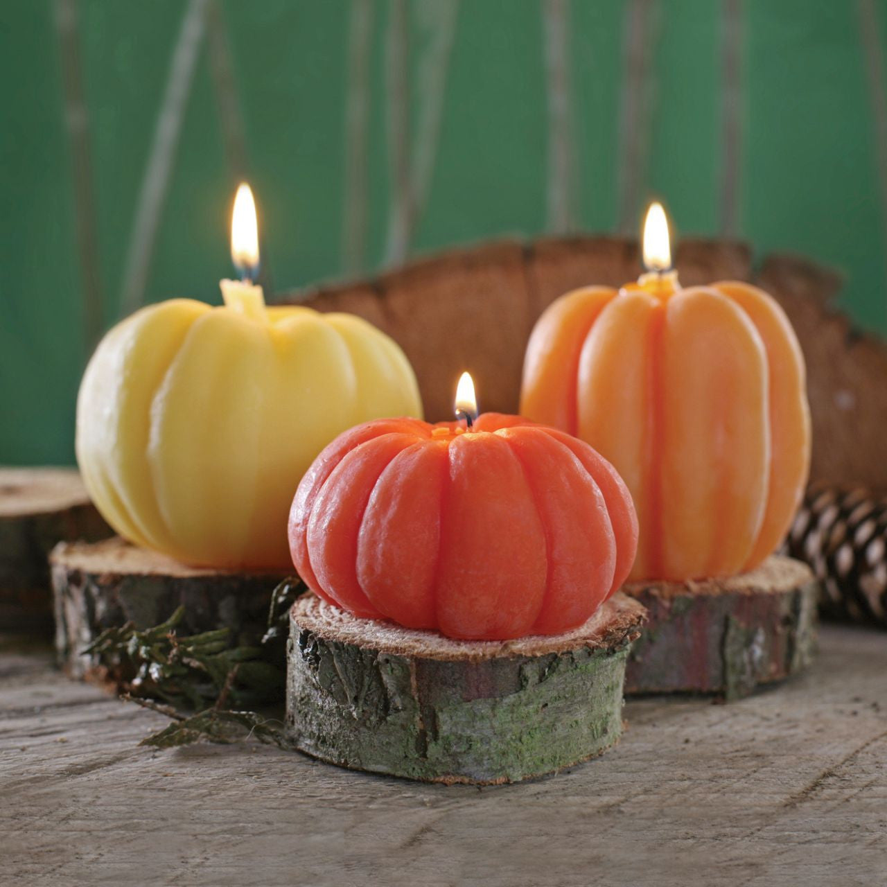 Three handcrafted beeswax pumpkin candles in dark orange, light orange, and natural colors, showcasing their unique designs and warm glow.