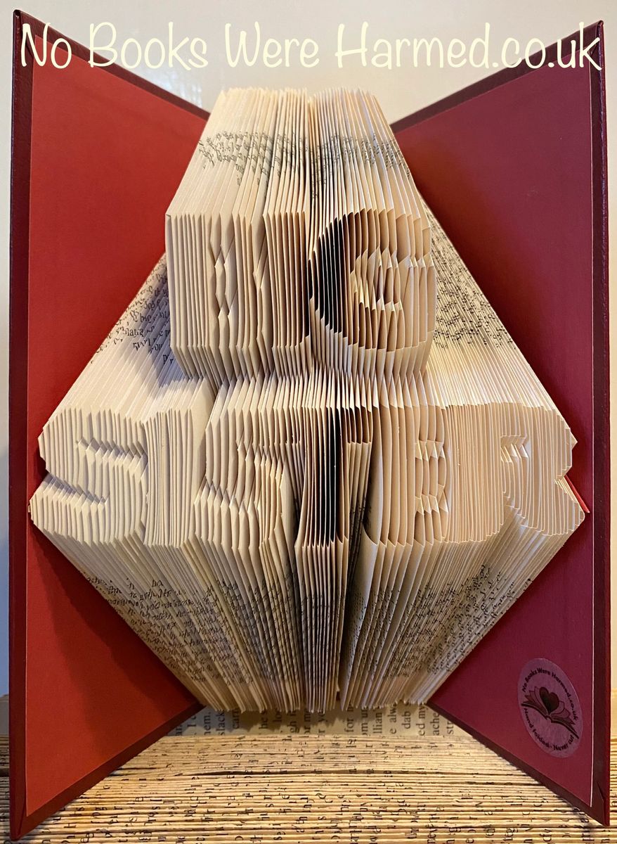 A beautifully handcrafted book art piece titled BIG SISTER, made from vintage books with intricately folded pages, showcasing unique designs and colors.