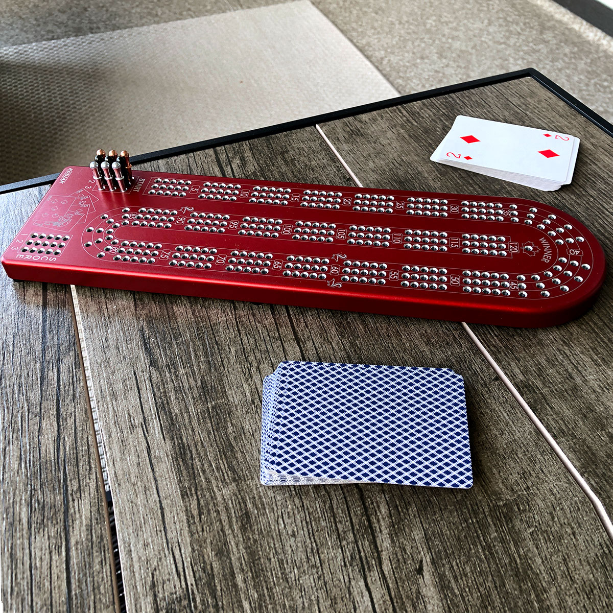 A premium Billet Aluminum Cribbage Board with anodized finishes in various colors, featuring large numbers and custom pegs.