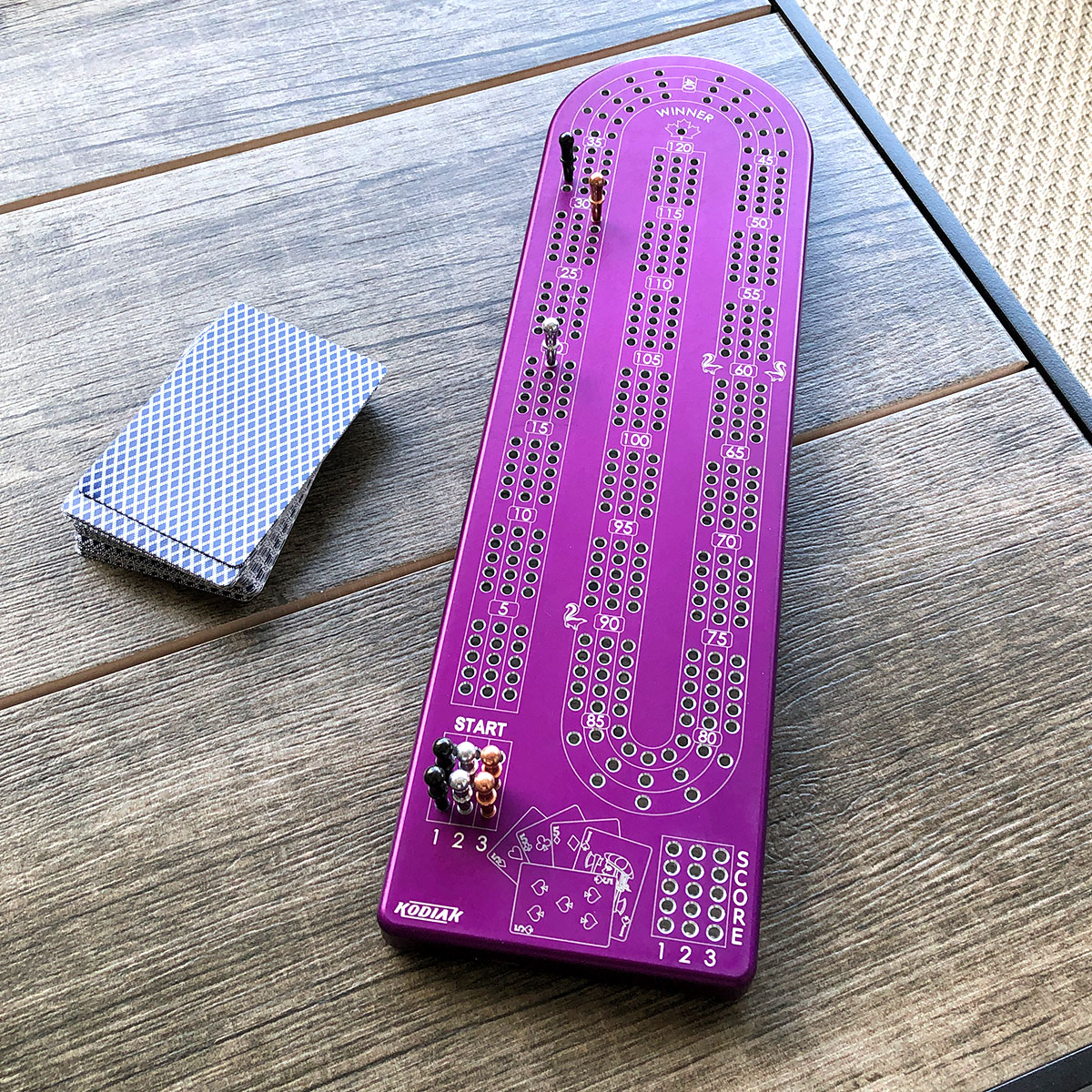 A premium Billet Aluminum Cribbage Board with anodized finishes in various colors, featuring large numbers and custom pegs.