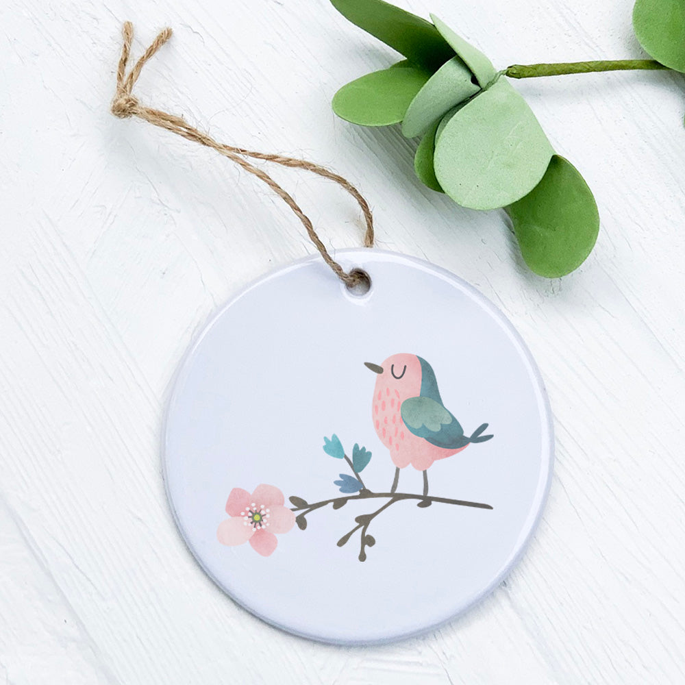 A beautiful porcelain ornament featuring a bird perched on cherry blossoms, showcasing vibrant colors and a glossy finish.