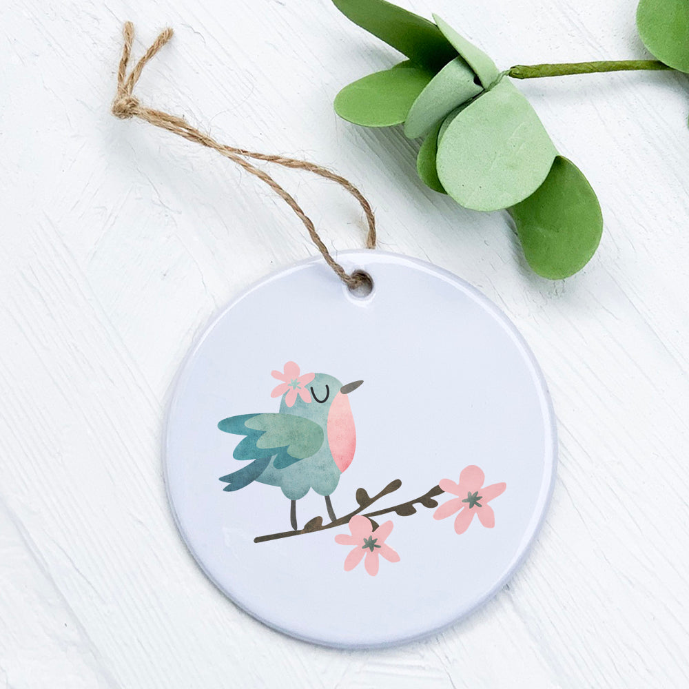 A beautifully crafted porcelain ornament featuring a bird perched on a floral branch, showcasing vibrant colors and a glossy finish.