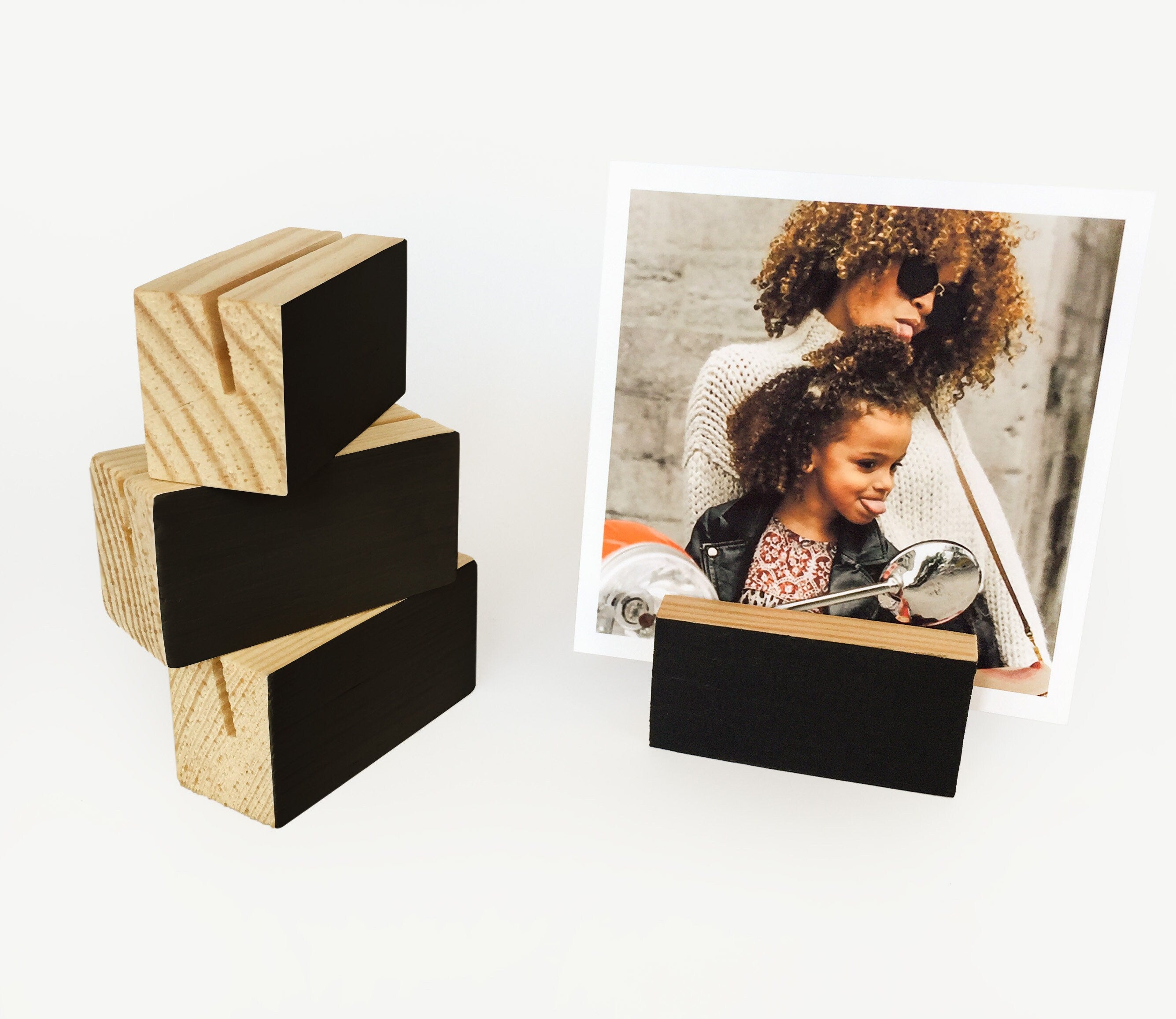 A stylish black wood block card holder displaying various art prints and photos, perfect for desks and shelves.