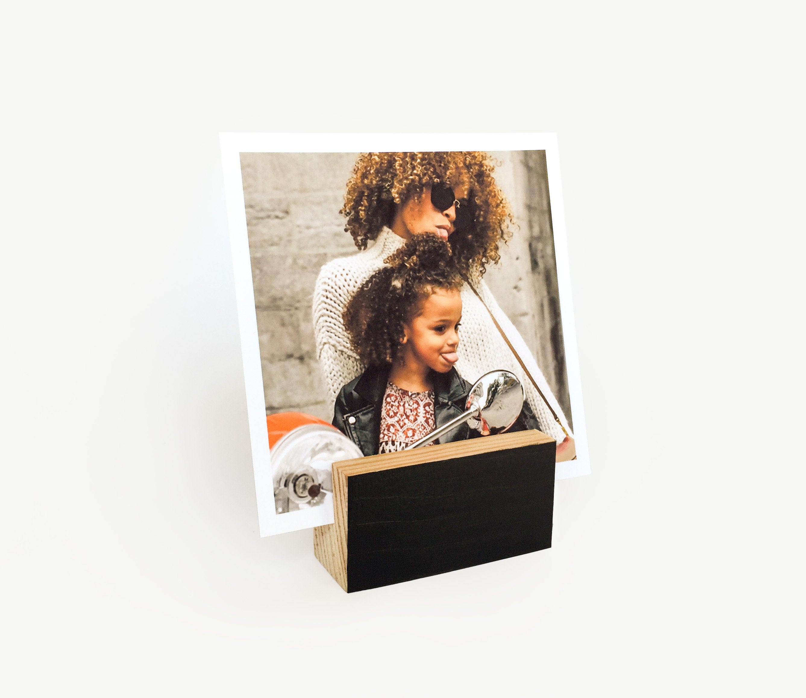 A stylish black wood block card holder displaying various art prints and photos, perfect for desks and shelves.