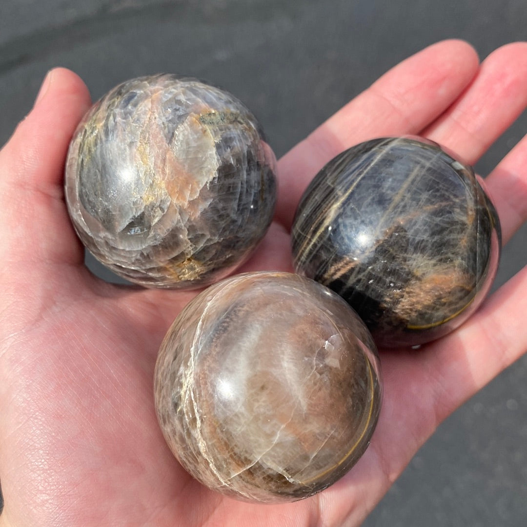 A beautiful Black Moonstone Sphere with a dark gray to black body and shimmering silvery sheen, perfect for meditation and emotional balance.