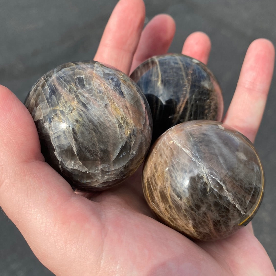 A beautiful Black Moonstone Sphere with a dark gray to black body and shimmering silvery sheen, perfect for meditation and emotional balance.