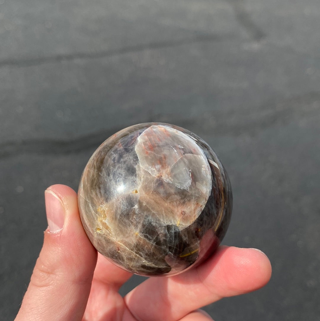 A beautiful Black Moonstone Sphere with a dark gray to black body and shimmering silvery sheen, perfect for meditation and emotional balance.