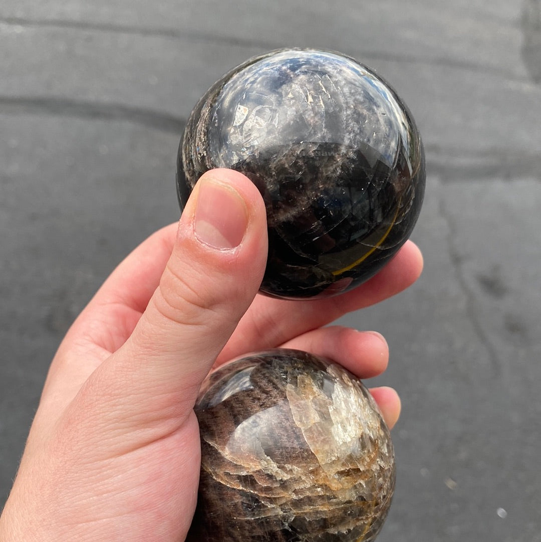 A beautiful Black Moonstone Sphere with a dark gray to black body and shimmering silvery sheen, perfect for meditation and emotional balance.