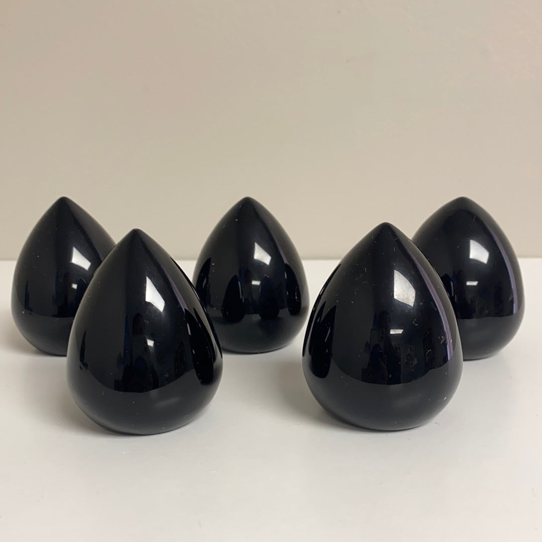 A polished Black Obsidian Cut Base Egg, showcasing its glossy surface and deep black color, standing 2.5 inches tall.