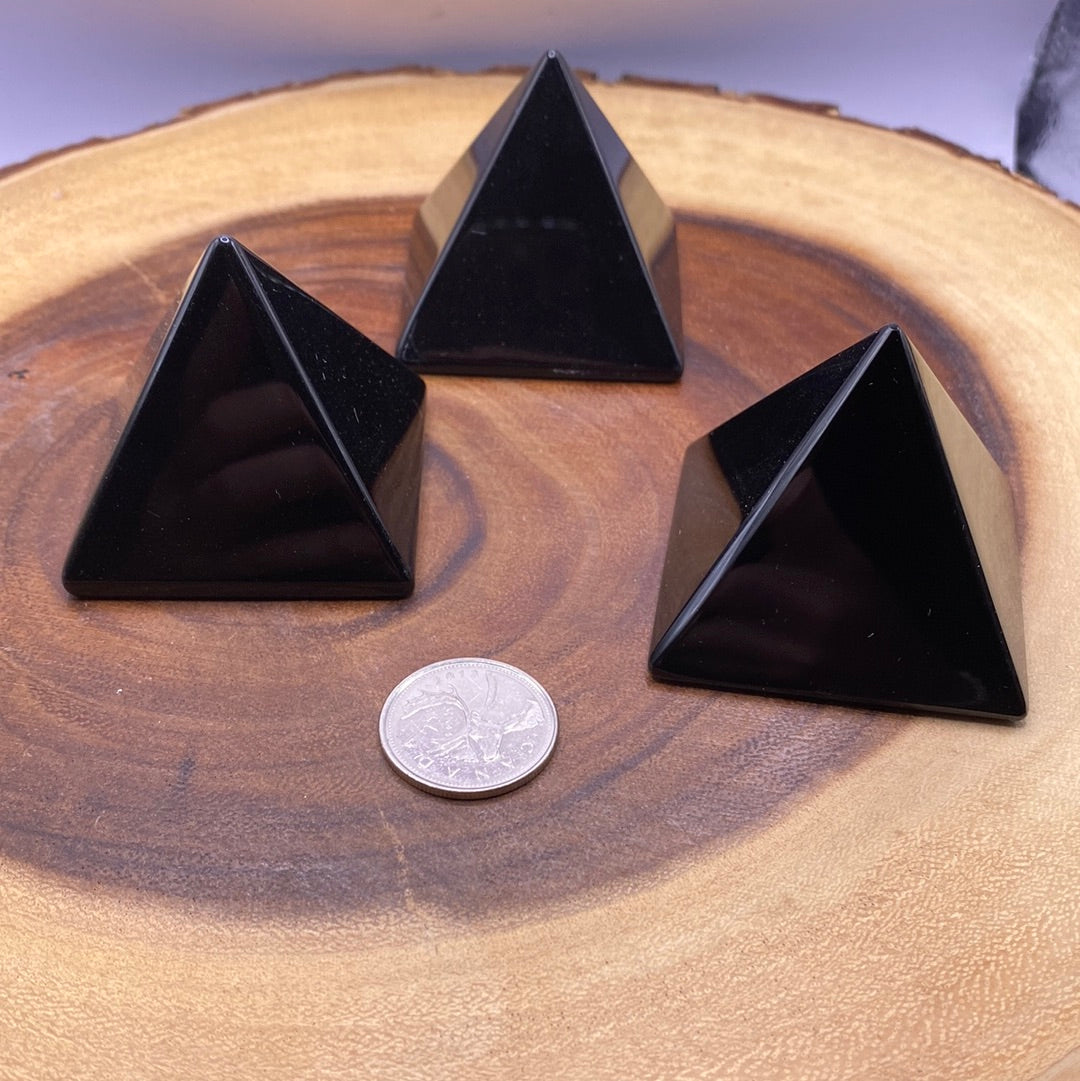 A polished Black Obsidian Pyramid reflecting dark hues, symbolizing healing and protection.