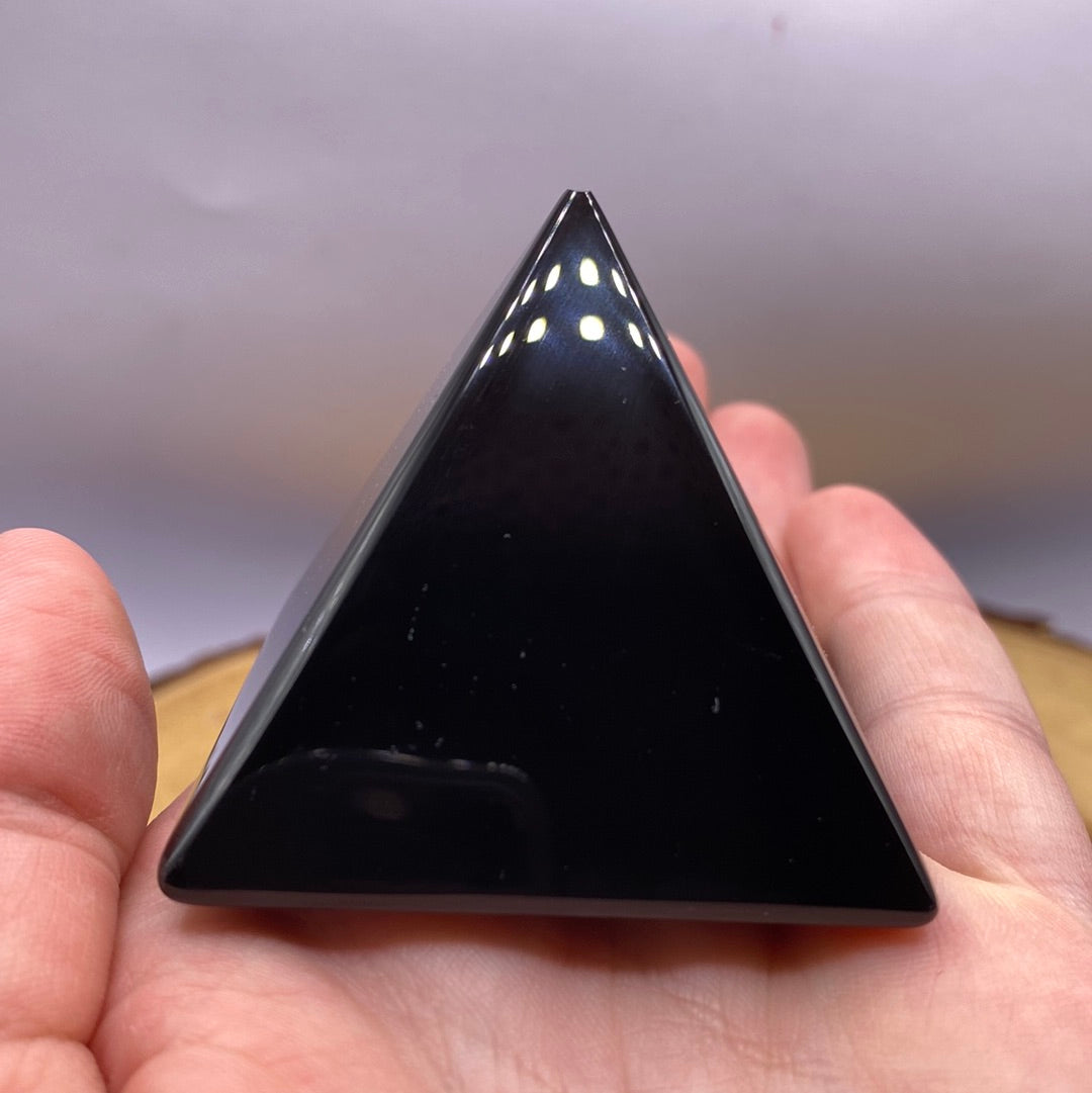 A polished Black Obsidian Pyramid reflecting dark hues, symbolizing healing and protection.