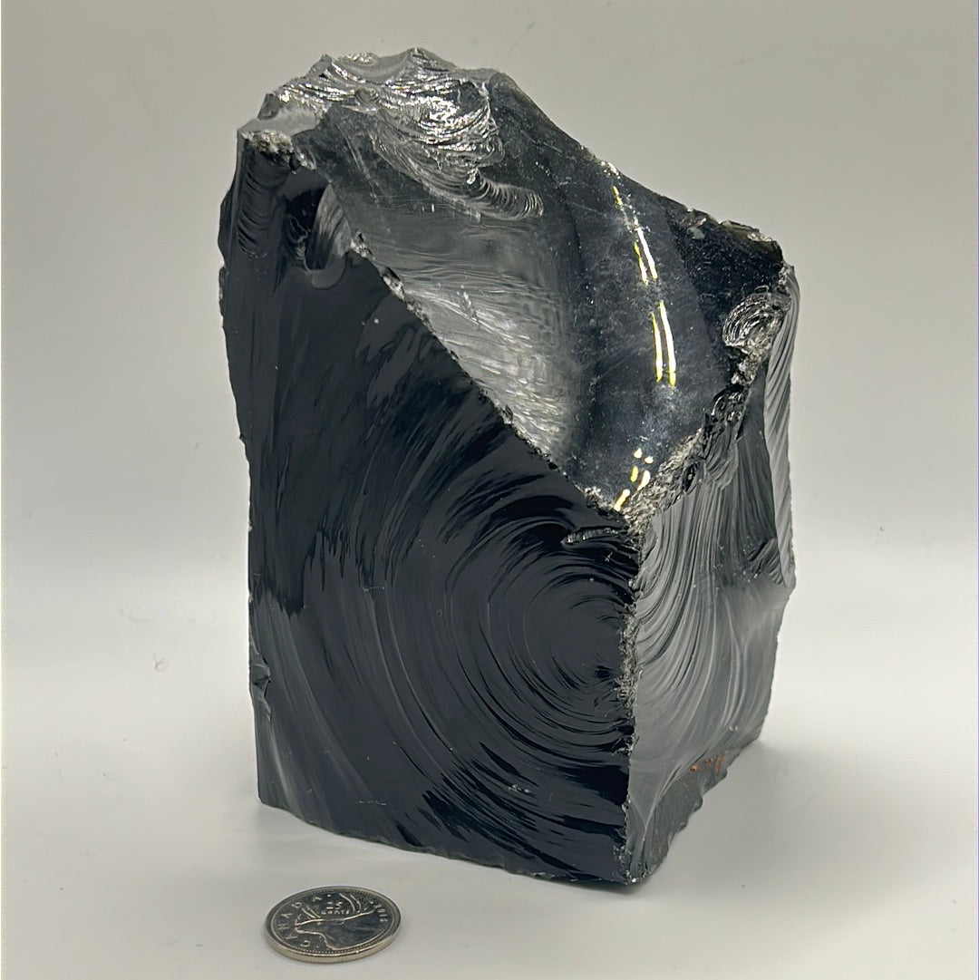 A rough cut freeform piece of Black Obsidian, showcasing its glossy black surface and unique shape, measuring approximately 5.5 inches by 4 inches.