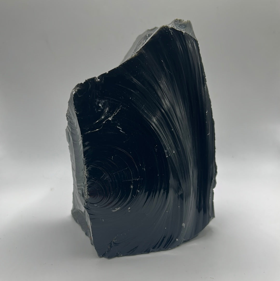 A rough cut freeform piece of Black Obsidian, showcasing its glossy black surface and unique shape, measuring approximately 5.5 inches by 4 inches.