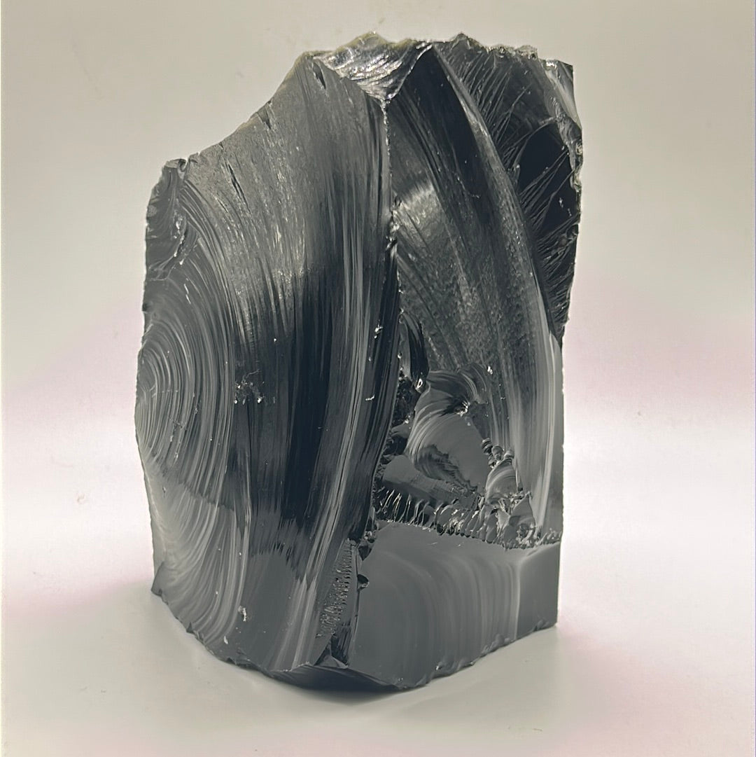 A rough cut freeform piece of Black Obsidian, showcasing its glossy black surface and unique shape, measuring approximately 5.5 inches by 4 inches.