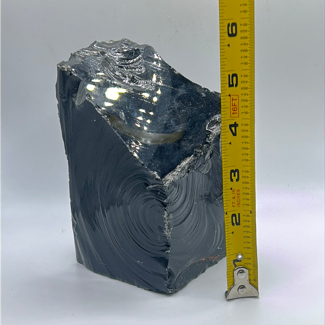 A rough cut freeform piece of Black Obsidian, showcasing its glossy black surface and unique shape, measuring approximately 5.5 inches by 4 inches.