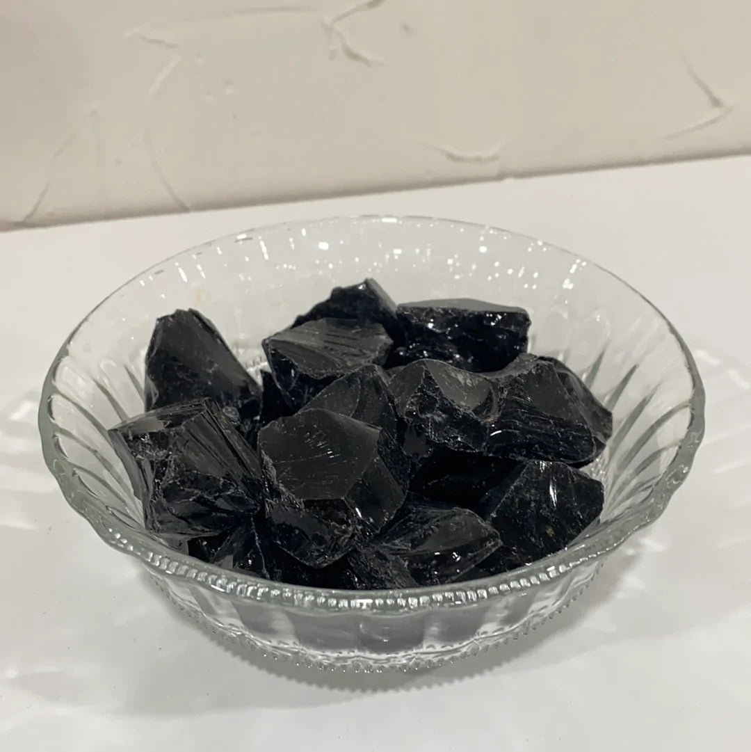 A collection of rough cut Black Obsidian pieces showcasing their glossy black surface and unique shapes.