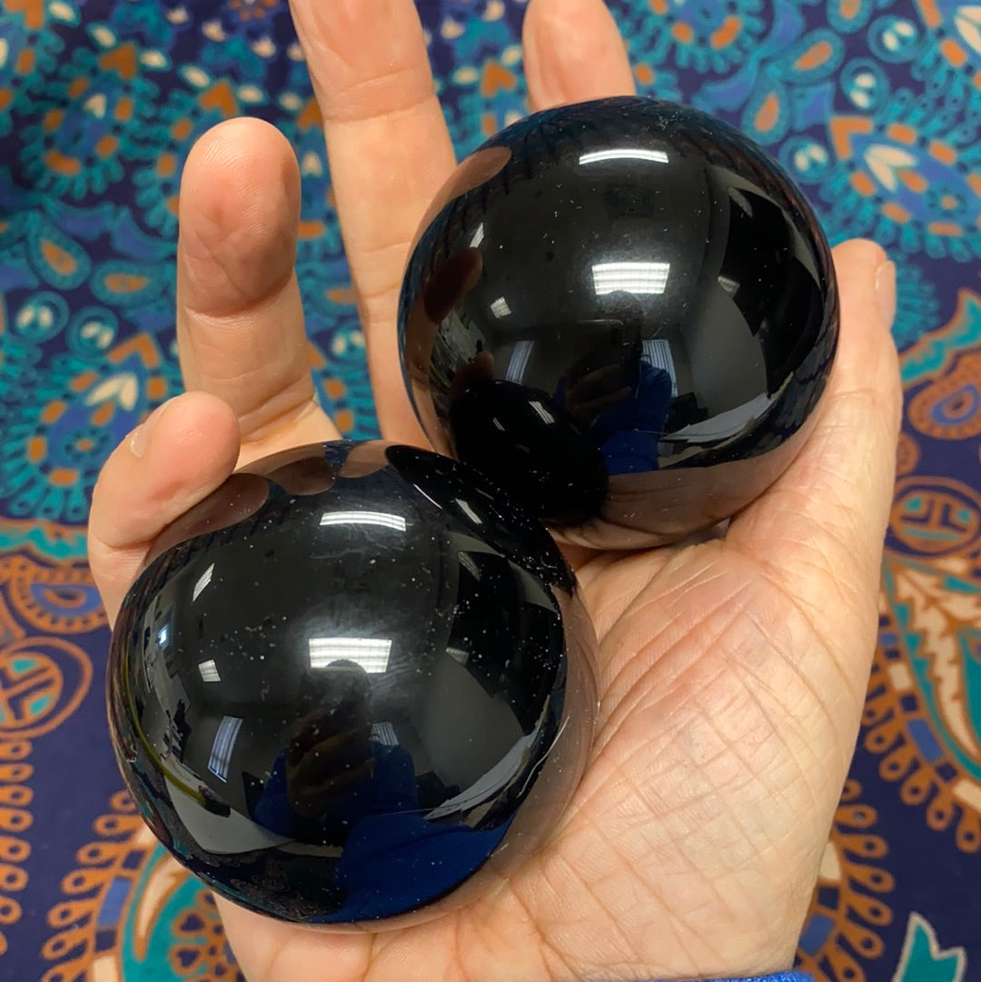 A polished Black Obsidian Sphere, approximately 2.5-3 inches in diameter, showcasing its unique glossy surface and deep black color.