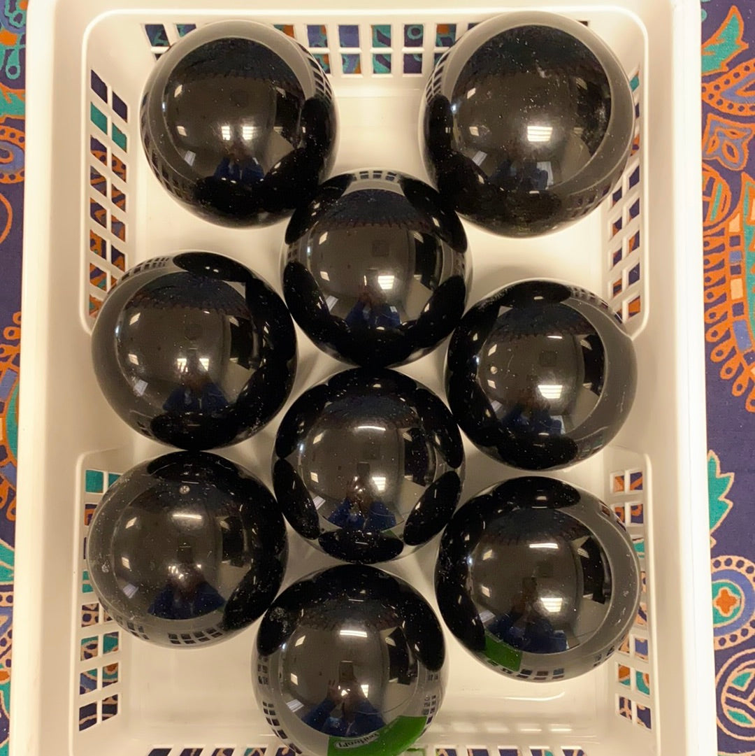 A polished Black Obsidian Sphere, approximately 2.5-3 inches in diameter, showcasing its unique glossy surface and deep black color.