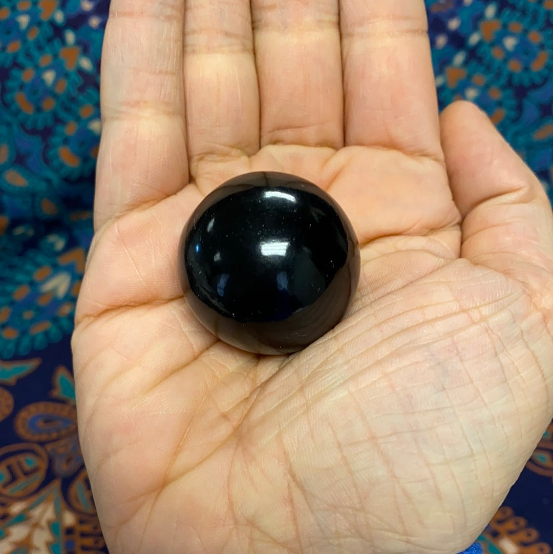 A polished Black Obsidian Sphere showcasing its smooth, glossy surface and deep black color, perfect for energy healing and decoration.