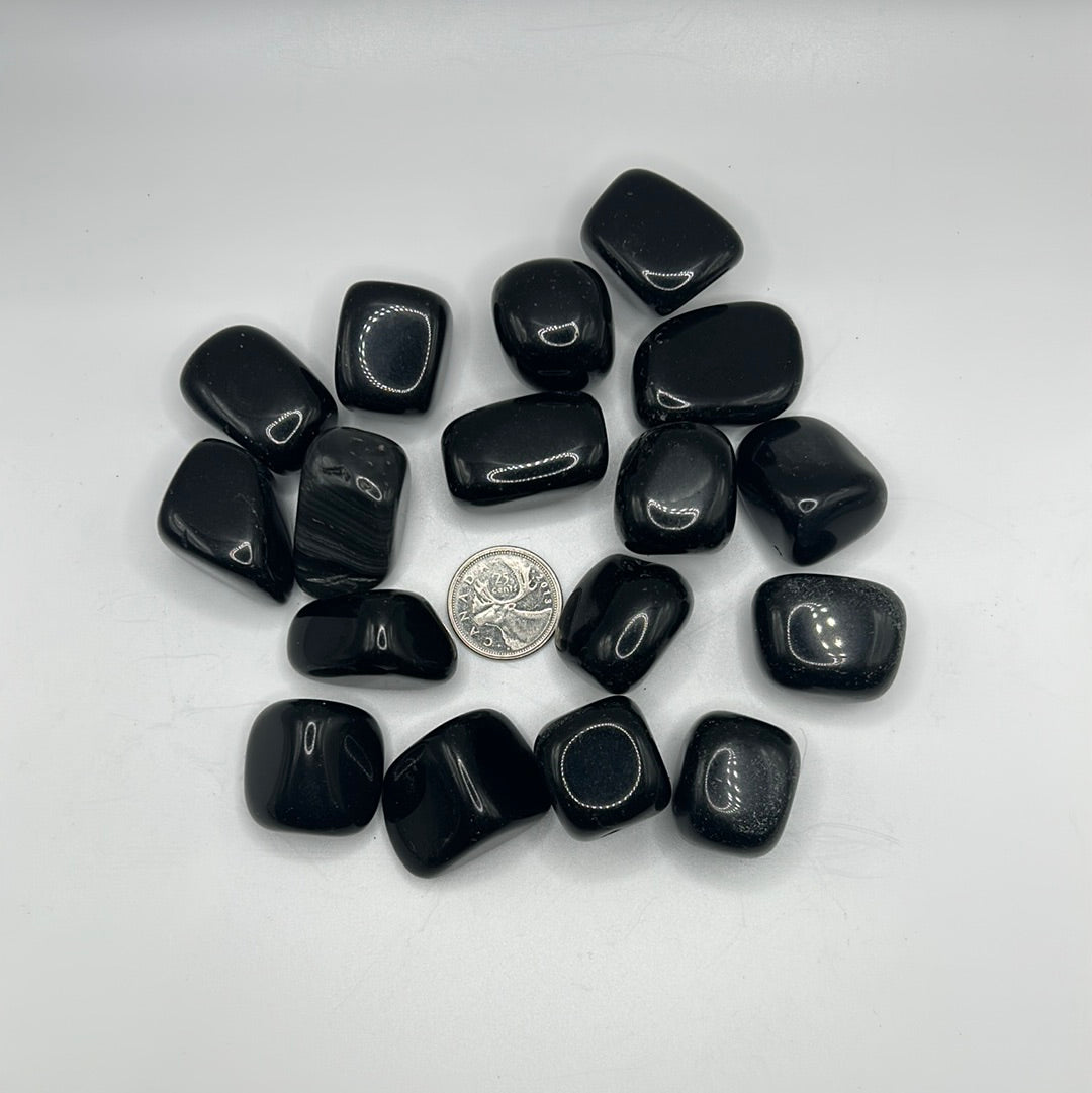 A collection of smooth, shiny Black Obsidian tumbled healing stones, showcasing their natural volcanic glass texture and dark color.