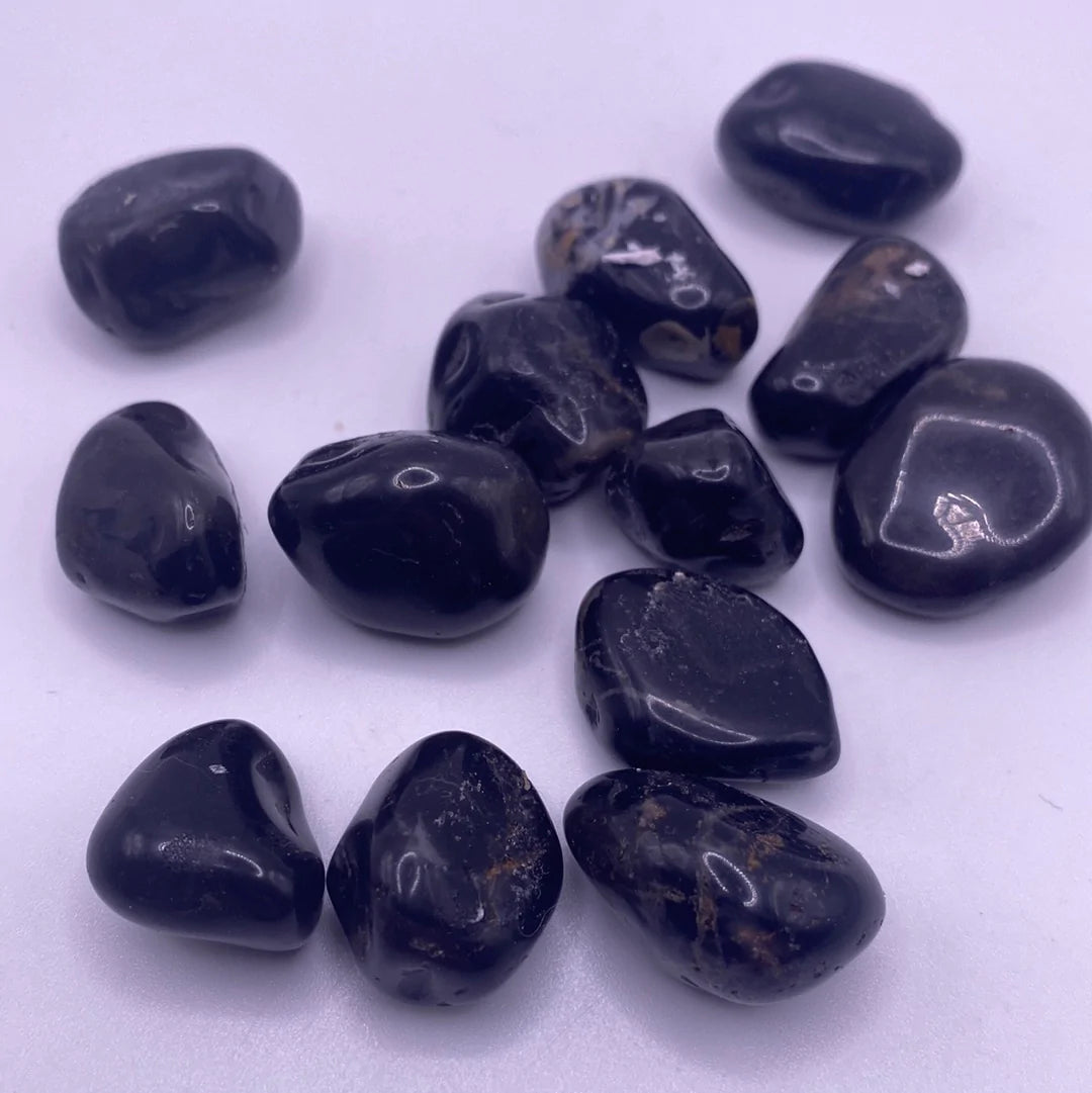 A collection of polished Black Onyx Tumbled Stones, showcasing their smooth, glossy surface and deep black color, ideal for protection and emotional strength.