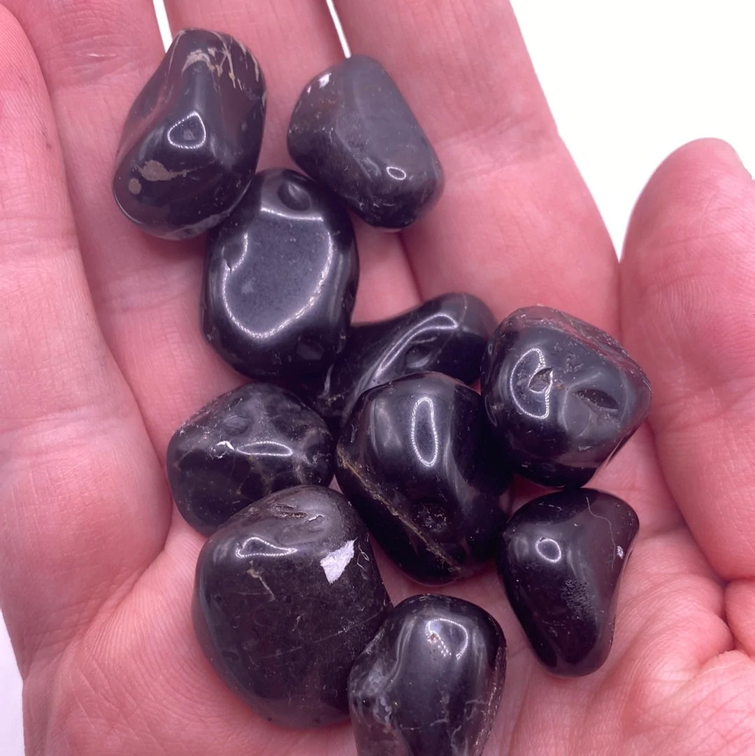 A collection of polished Black Onyx Tumbled Stones, showcasing their smooth, glossy surface and deep black color, ideal for protection and emotional strength.